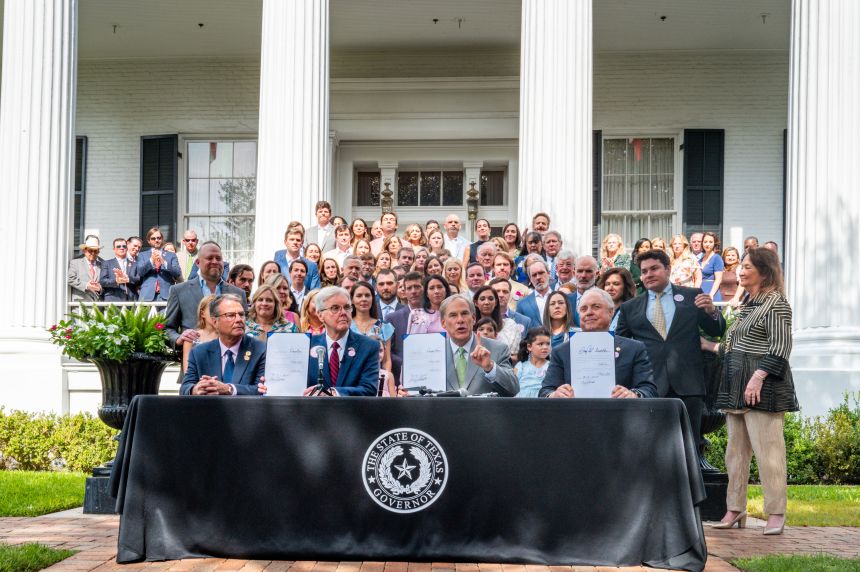 Texas lawmakers display newly signed bills in response to the deadly summer flooding during a bill ceremony at the Governor's Mansion in Austin.