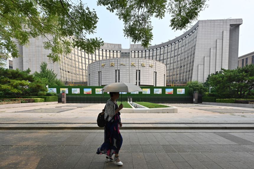A woman walks past the headquarters of the People's Bank of China, the country's central bank, in Beijing on July 9, 2024.