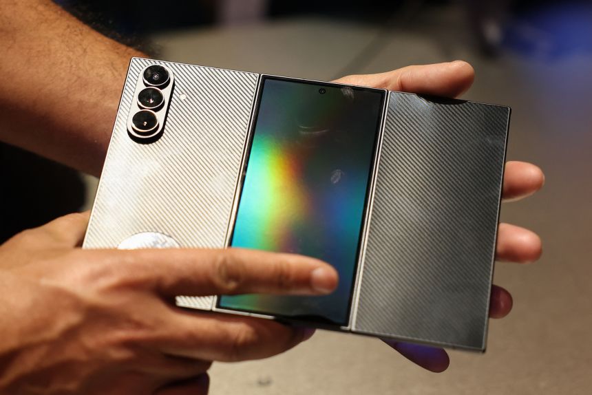 Attendees fold the display of the Samsung Galaxy Z TriFold smartphone during the Samsung Electronics First Look event ahead of the Consumer Electronics Show (CES) in Las Vegas on January 4, 2026.