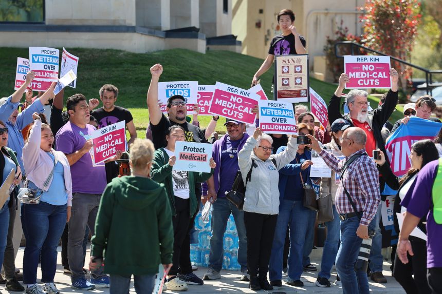 Protesters chant and hold signs outside of Rep. Young Kim's Anaheim Hills office to protest the recent reconciliation budget bill that they say could lead to billions of dollars of cuts to SNAP, Medicaid and other federal programs in Anaheim Hills, California, on March 18, 2025.