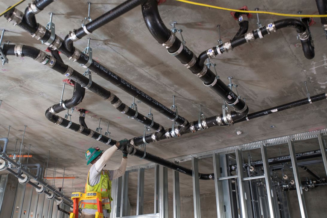 A worker applies aluminum strapping to pipes during construction on a project for affordable housing at Brooklyn Basin in Oakland, California, on November 12, 2019.