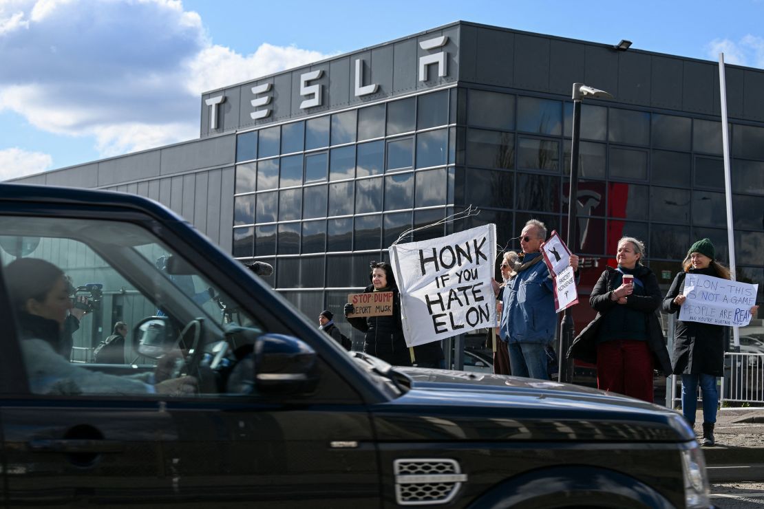 Demonstrators hold anti-Tesla posters during a protest encouraging people to boycott Tesla outside the Tesla Centre Park Royal in London, Britain, March 15, 2025.
