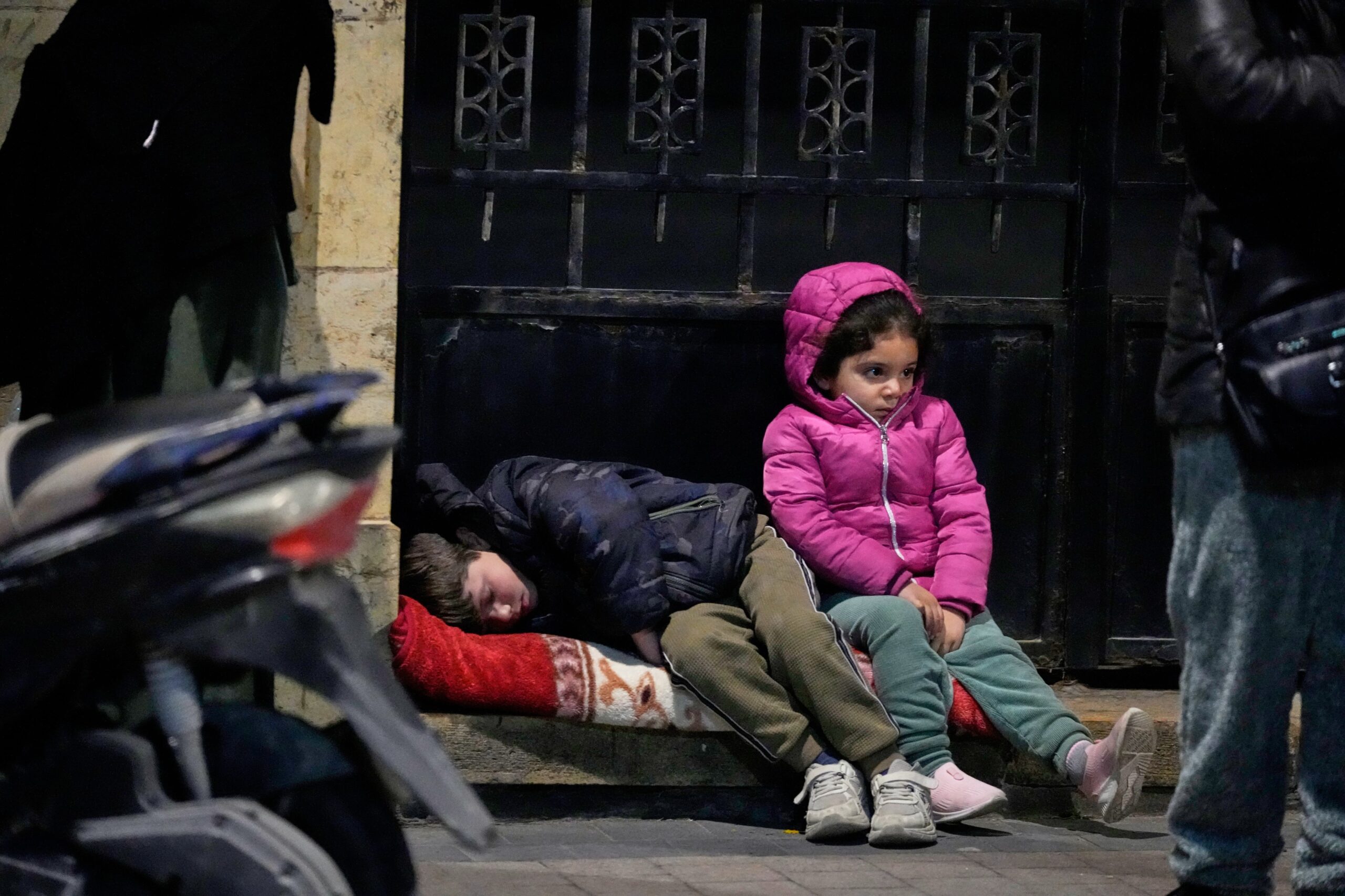 Mohammad Zaatari/AP via CNN NewsourceChildren sit on a sidewalk as displaced families fleeing Israeli strikes in southern Lebanon arrive in the southern port city of Sidon