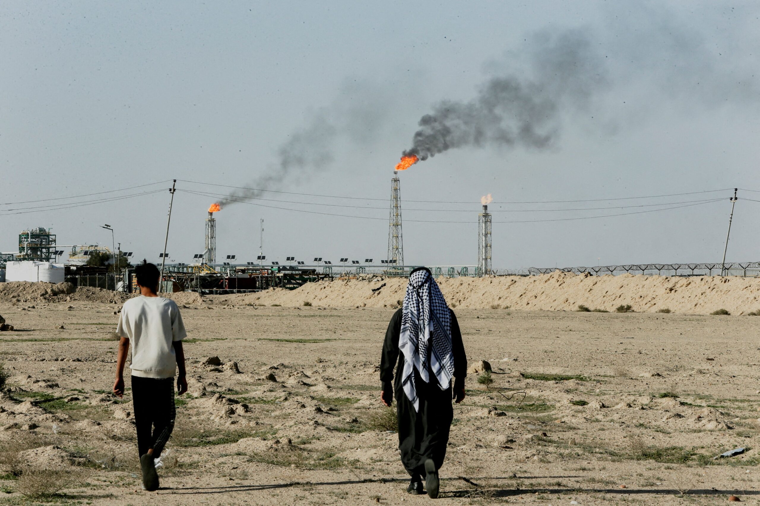Essam Al-Sudani/Reuters via CNN NewsourcePeople walk on farmland near the Zubair oil field in Zubair Mishrif