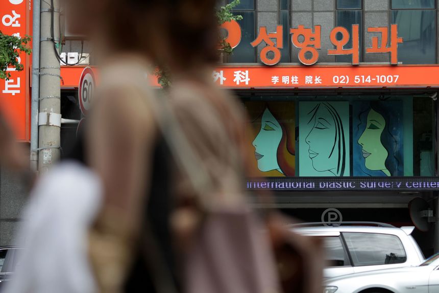 Signs for plastic surgery clinics are displayed on a building in the Apgujeong-dong area of Gangnam district in Seoul, South Korea, on August 3, 2013.
