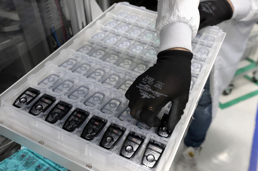 A worker assembles electronic car keys at a manufacturing plant in Mexico. The small, handheld remote controls are assembled in Mexico, but they cross borders in North America several times before being finished, like countless other auto parts and products.